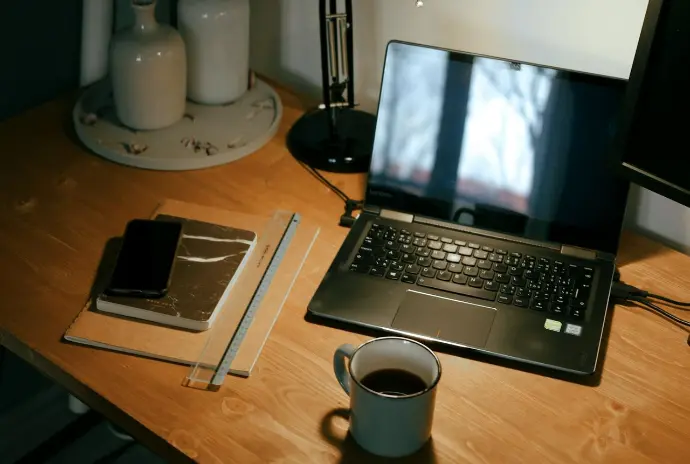 black laptop computer beside white ceramic mug on brown wooden table